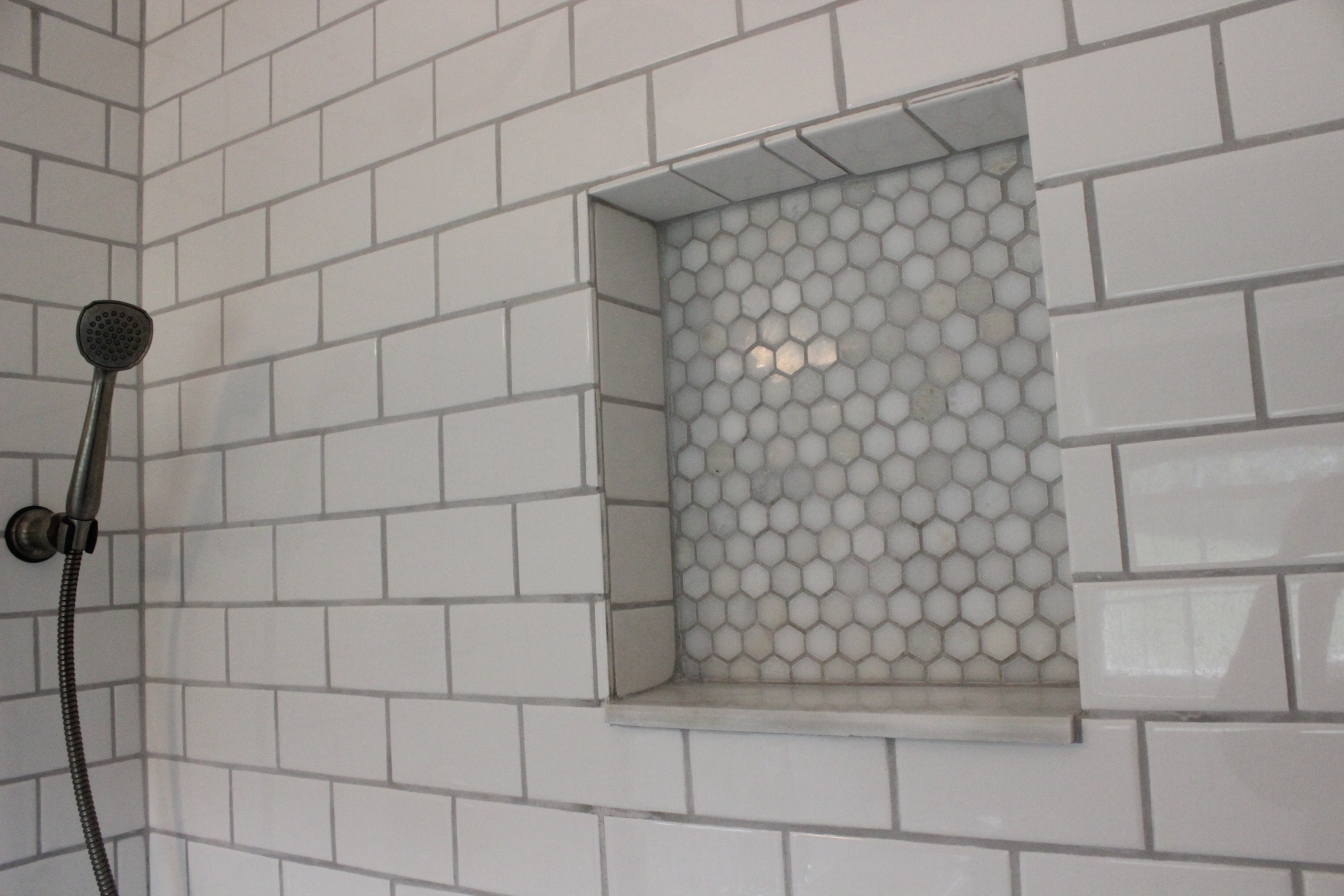 We did white subway tiles in the shower, and marble hex tile in the niche a...